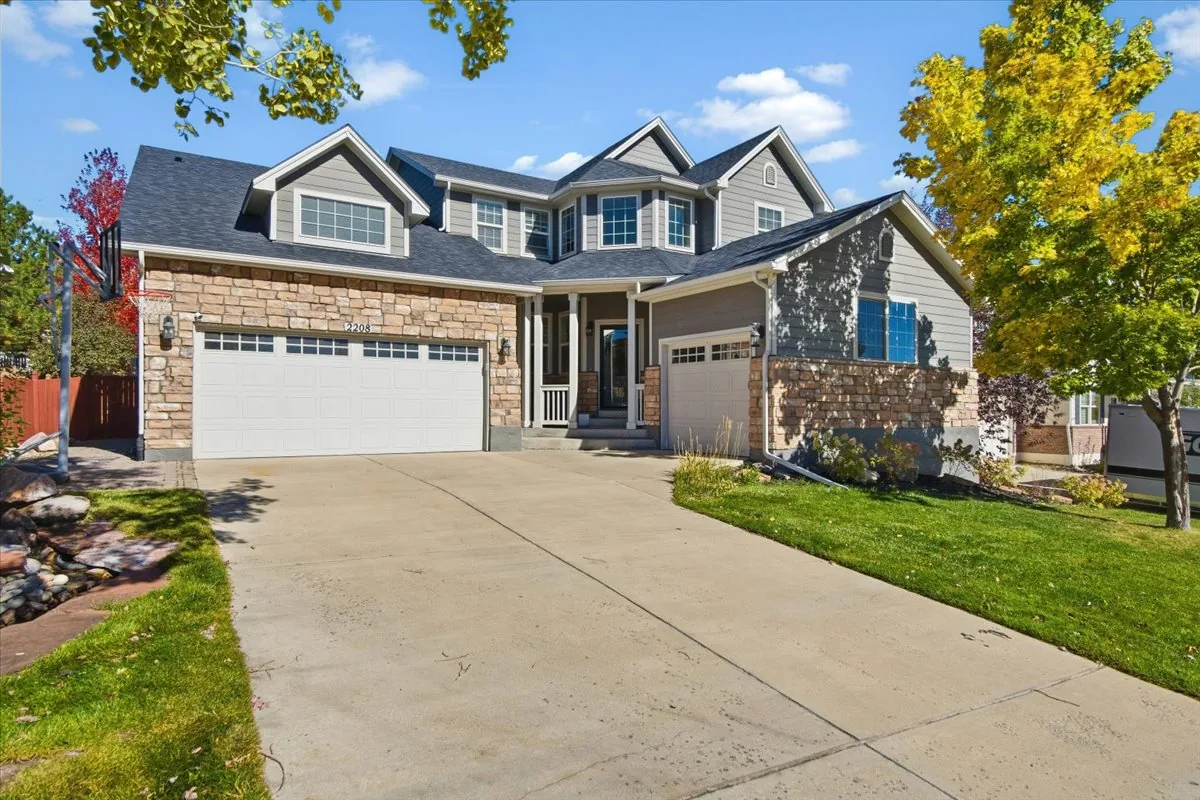 Two-story Castle Rock home with stone exterior, peaked roofs, and autumn foliage on a sunny day