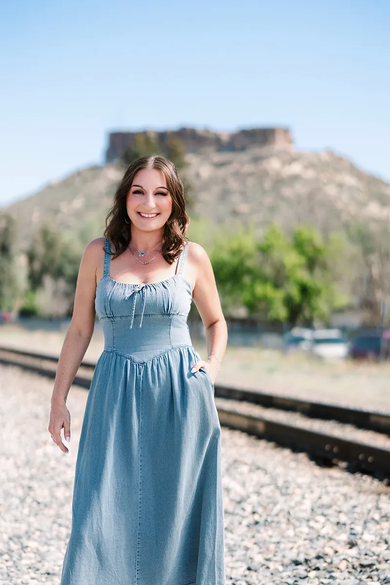 Jessica Lentz in a denim dress on the railroad tracks below the Castle Rock butte